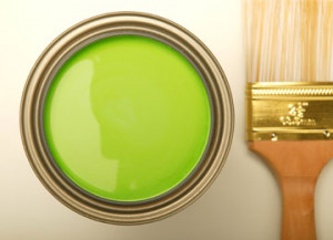 A paint brush next to a tin of green paint
